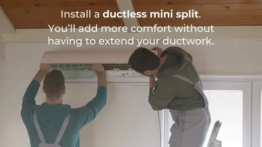 Two workers install a ductless mini split on a white wall.