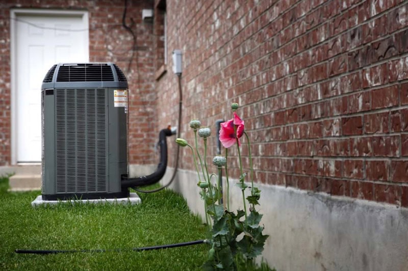 Blog Title: How Does an Air Conditioner Work? Photo: AC Unit outside next to a brick home