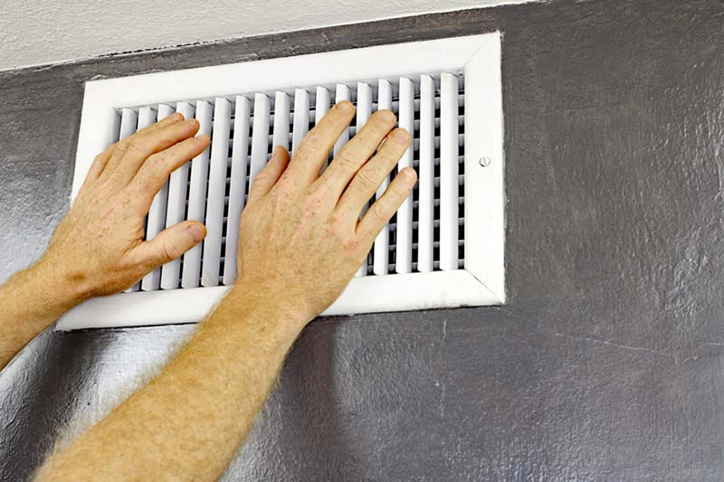 Hands in front of white wall vent