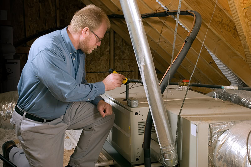 HVAC technician performing maintenance on furnace in attic.